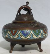 An Oriental bronze and champleve incense burner and cover on three feet