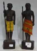 A pair of carved wooden figures of a Native man and woman with cloth skirts,