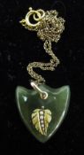 A 9 ct gold and greenstone shield shaped pendant applied with gold and seed pearl leaf,