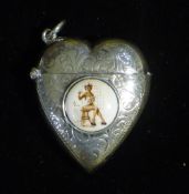 A silver heart shaped vesta depicting a lady draped in a towel