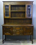 An Arts & Crafts oak sideboard with leaded glaze doors