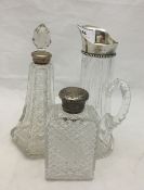 A silver top glass jug and two scent bottles