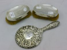 A silver backed mirror and two clothes brushes