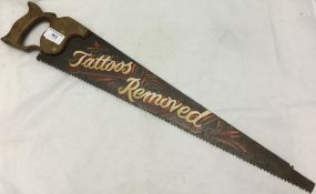 A painted saw inscribed "Tattoo's Removed"
