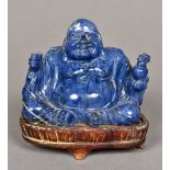 A Chinese carved lapis Buddha Modelled seated, standing on a wooden plinth base.