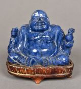 A Chinese carved lapis Buddha Modelled seated, standing on a wooden plinth base.