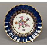 A Worcester porcelain dish Of gilt heightened scalloped shape, centrally painted with floral sprays,