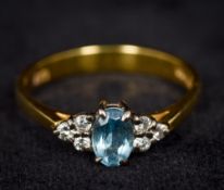 A modern 9 ct gold diamond ring Centred with a facet cut oval blue stone flanked by six smaller