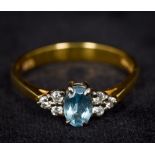 A modern 9 ct gold diamond ring Centred with a facet cut oval blue stone flanked by six smaller