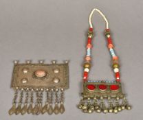 A Tibetan inscribed cabochon set white metal pendant Together with another with beaded necklace.