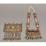 A Tibetan inscribed cabochon set white metal pendant Together with another with beaded necklace.