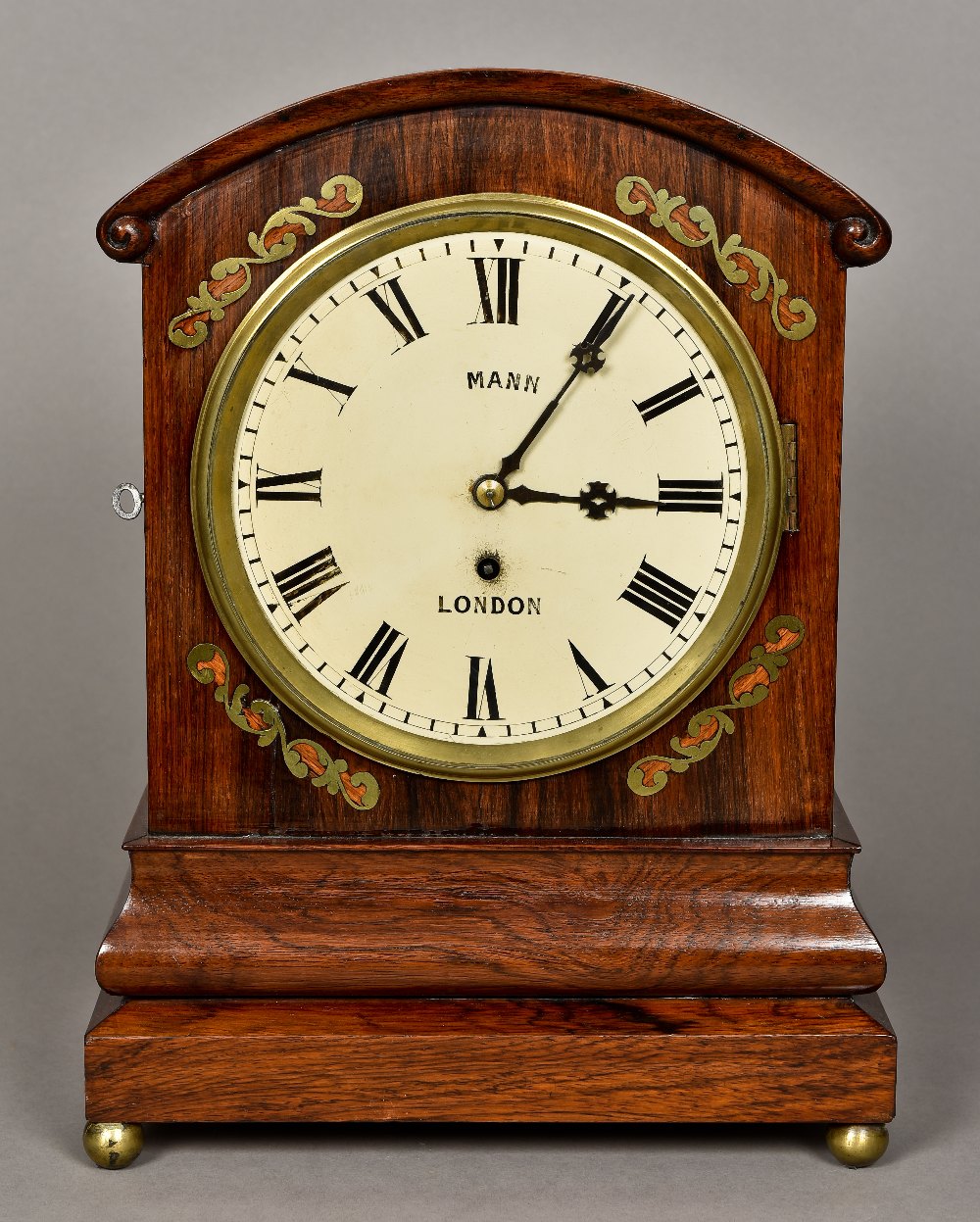 A Victorian brass inlaid walnut bracket clock The scroll carved domed top above the white dial with