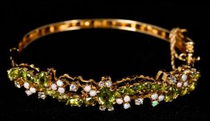 A 14 K gold, diamond, opal and peridot set bracelet Of pierced scrolling bangle form. 6.5 cm wide.