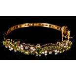 A 14 K gold, diamond, opal and peridot set bracelet Of pierced scrolling bangle form. 6.5 cm wide.