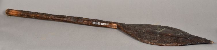 A North American Native Indian wooden paddle The blade carved with two figures rowing a canoe.