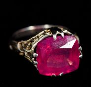 An 18 K white gold single stone ring, possibly ruby The facet cut stone set above pierced shoulders.