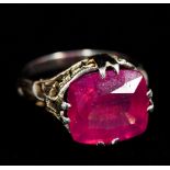 An 18 K white gold single stone ring, possibly ruby The facet cut stone set above pierced shoulders.