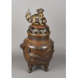 A large Oriental patinated bronze koro The pierced top surmounted with a dog-of-fo finial,