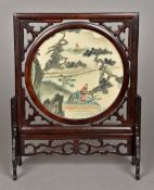 A Chinese hardwood table screen The central circular swivel panel printed with figures in