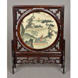 A Chinese hardwood table screen The central circular swivel panel printed with figures in