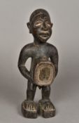 An African tribal carved wooden figure Modelled as a male with a glass inset protruding stomach.