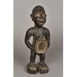 An African tribal carved wooden figure Modelled as a male with a glass inset protruding stomach.