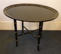 A 19th century papier mache tray top table The dished oval top with a band of gilt floral