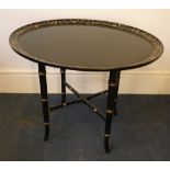A 19th century papier mache tray top table The dished oval top with a band of gilt floral
