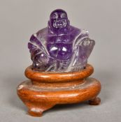 A Chinese carved amethyst Buddha Modelled seated, on a carved wood plinth base. 6 cm high overall.