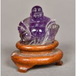 A Chinese carved amethyst Buddha Modelled seated, on a carved wood plinth base. 6 cm high overall.