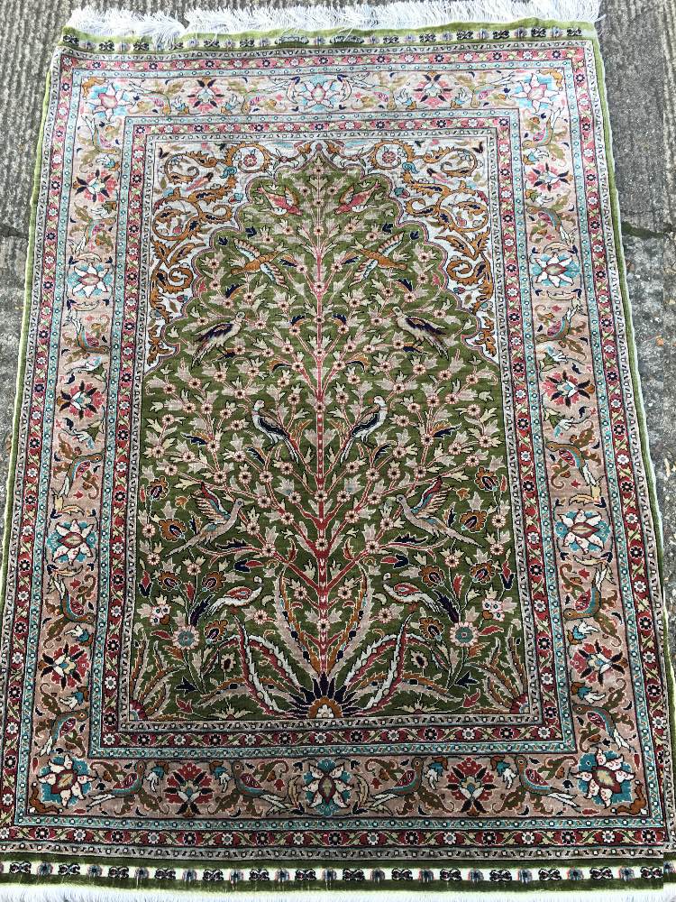 A Turkish silk prayer rug The green mihrab field enclosing a tree of life and exotic birds within