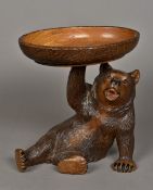 A Black Forest carved bear Modelled recumbent, holding aloft a bowl inscribed Interlaken.