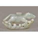 A Chinese carved white jade mythical horse Worked above stylised waves. 8 cm wide.