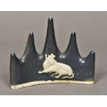 A Chinese porcelain brush rest Relief moulded with a mythical beast with allover blue/black glaze.