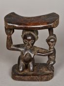 An African tribal carved wooden neck rest Carved with a crouching female figure and an infant. 18.