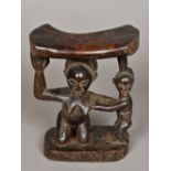 An African tribal carved wooden neck rest Carved with a crouching female figure and an infant. 18.