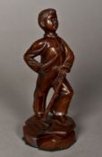 A Russian Revolutionary Period carved wooden figure of a boy Standing proud, leaning on a hammer,