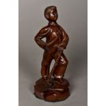 A Russian Revolutionary Period carved wooden figure of a boy Standing proud, leaning on a hammer,
