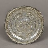 A Continental silver dish Of scrolling circular form centred with cherubs. 14 cm diameter.