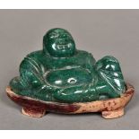 A Chinese carved green stone Buddha Modelled recumbent, on carved wood plinth base.