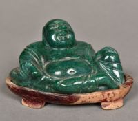 A Chinese carved green stone Buddha Modelled recumbent, on carved wood plinth base.