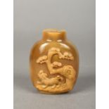 A Chinese carved agate snuff bottle Worked with a temple lion beneath a pine tree. 7.5 cm high.