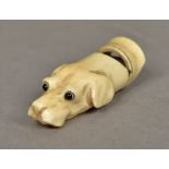 A carved ivory whistle Worked as a dog's head with glass eyes. 4.5 cm long.