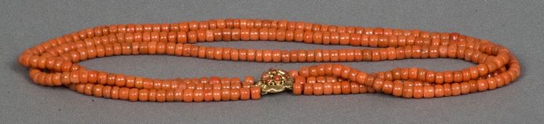 A three strand coral bead necklace Set with a gold clasp. Approximately 47 cm long.