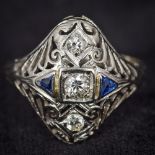 An Art Deco style 18K white gold diamond and sapphire set ring Of pierced domed navette form. 1.