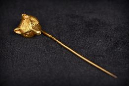 An unmarked gold and diamond stick pin The top formed as a fox mask with diamond inset eyes.