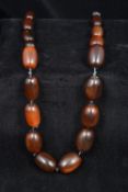 A Chinese carved horn graduated bead necklace Secured with a jade toggle. 58 cm long.