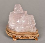 A Chinese carved quartz Buddha Modelled recumbent on a carved wood plinth base. 10 cm high overall.