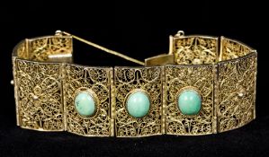 A Continental silver filigree bracelet Of segmented form, set with three turquoise cabochons.