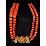 A two strand coral bead necklace Set with a coral mounted 18 ct gold clasp. 69 cm long.
